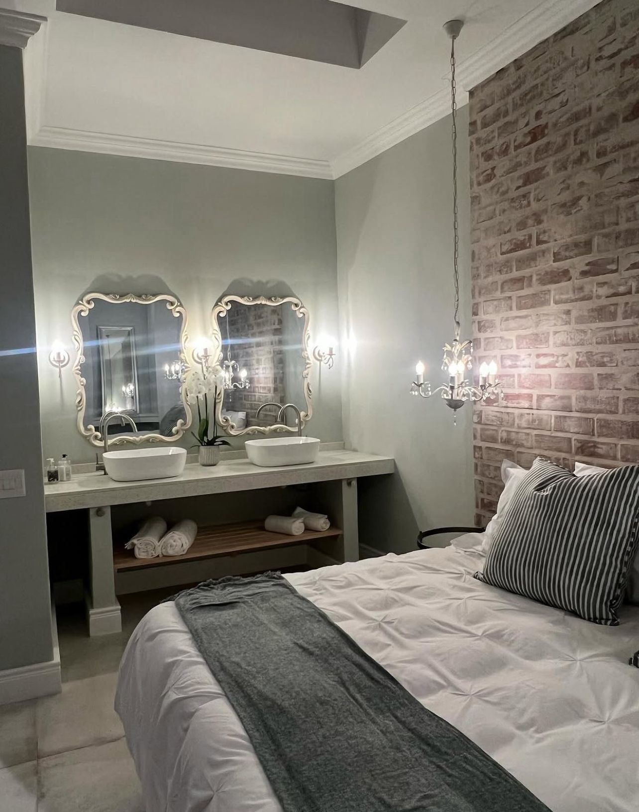 Bathroom vanity with chandelier and brick wall